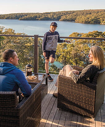 A family relax on the balcony at Hilltop Cottage, Royal National Park. Photo: John Spencer/DPIE